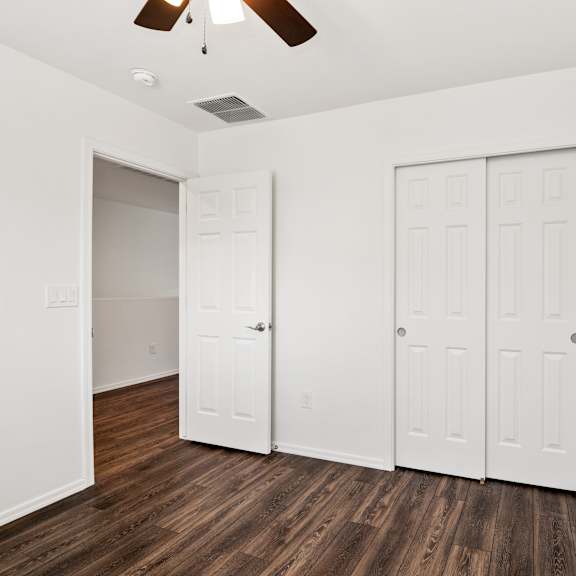 a bedroom with two closets and a ceiling fan