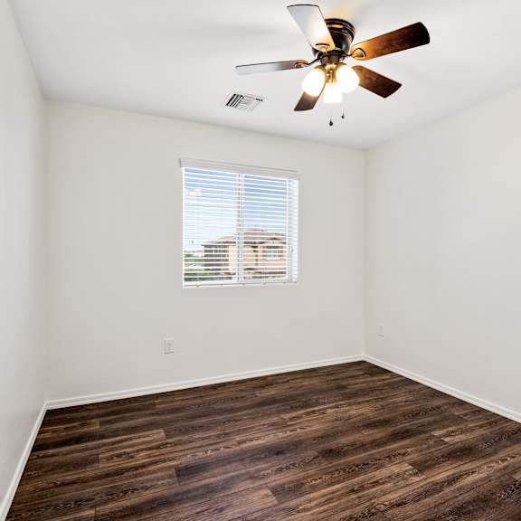 an empty room with a ceiling fan and a window