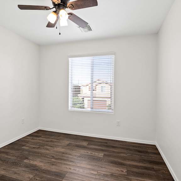 an empty room with a ceiling fan and a window