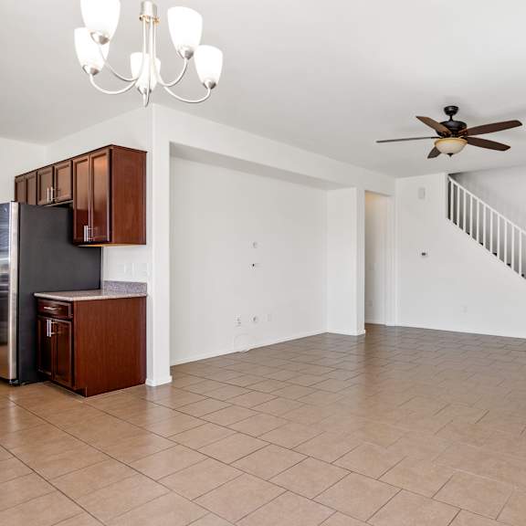 an empty living room with a ceiling fan and a staircase