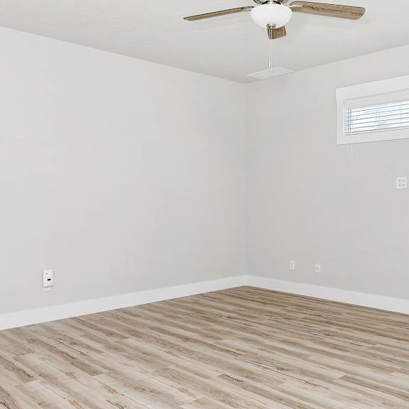 a room with a ceiling fan and wooden flooring.