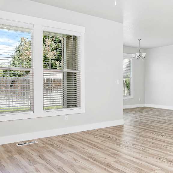a room with wooden flooring and a window with blinds.