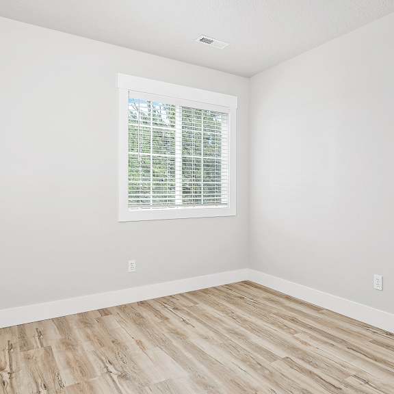 a room with a window and wooden flooring.