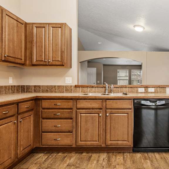 a kitchen with wooden cabinets and a black trash can.