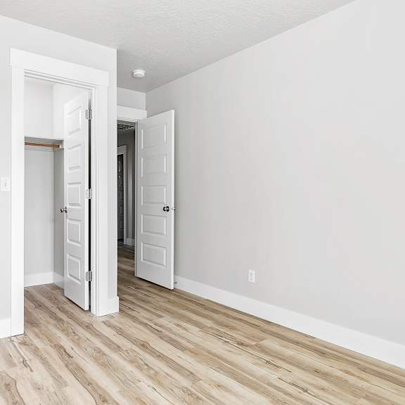 a white door is open to a hallway with wood flooring.
