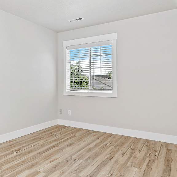 a room with a window and wooden flooring.