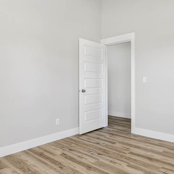 a room with a white door and wooden flooring.