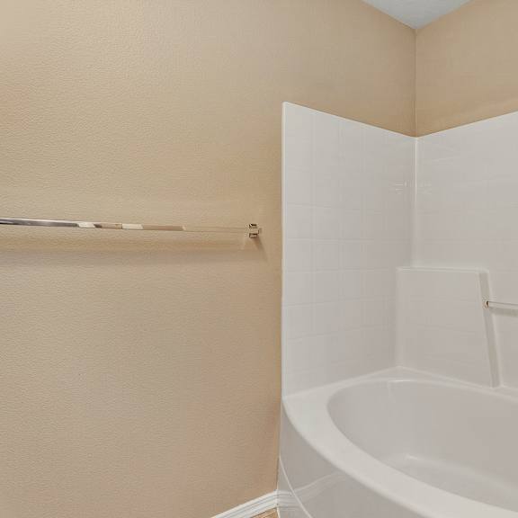 a white bathtub in a bathroom with beige walls.