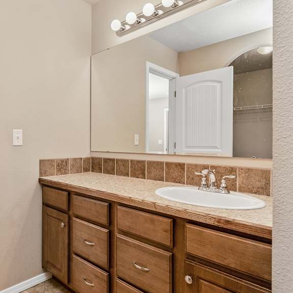 a bathroom with a sink, mirror, and cabinets.