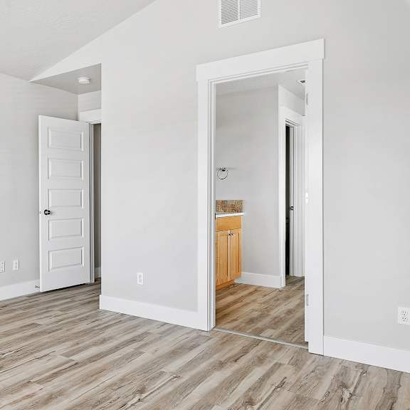a room with a white door and a wooden floor.