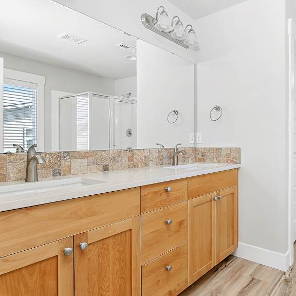 a bathroom with two sinks and wooden cabinets.