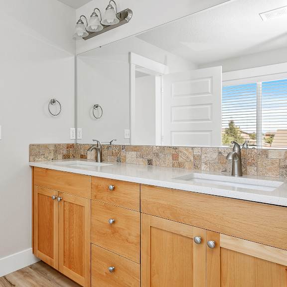 a bathroom with a white ceiling fan, a white counter top, and wooden cabinets.