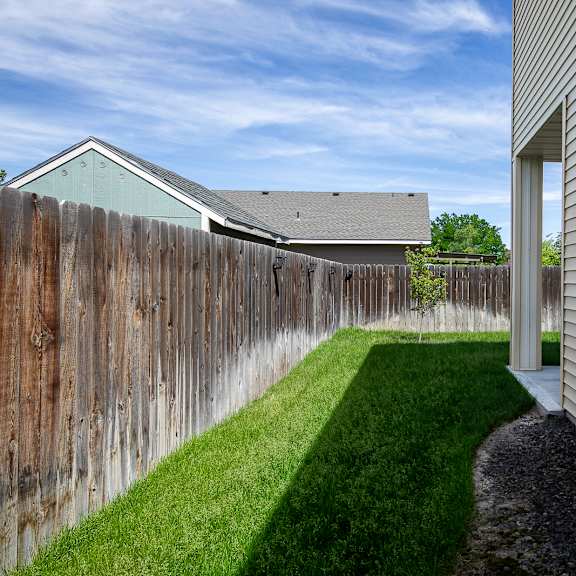 a house with a wooden fence and a green lawn.