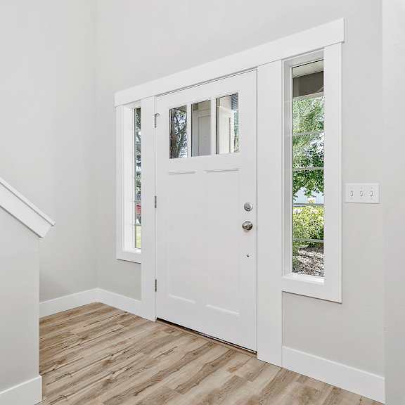 a white door with a glass window is in a room with a wooden floor.