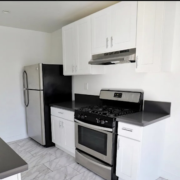a modern kitchen with black countertops and stainless steel appliances.