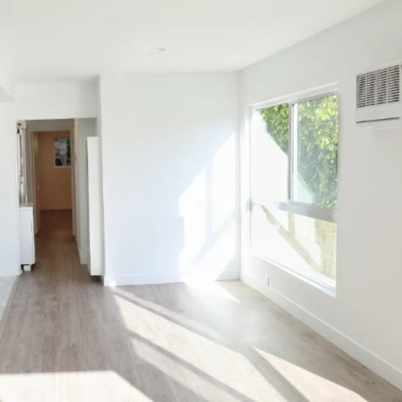 a white hallway with a brown door and a window on the right.