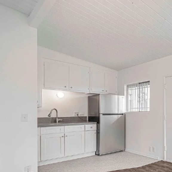 a white kitchen with a refrigerator, sink, and cabinets.