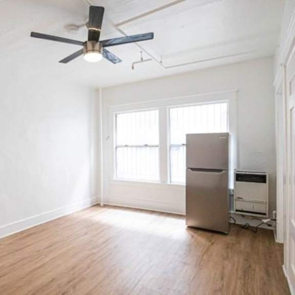 a room with a ceiling fan and a refrigerator.