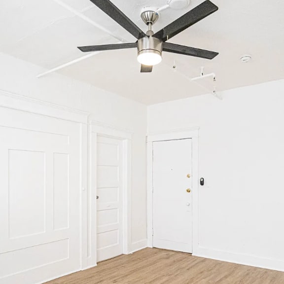 a room with a ceiling fan and two doors.