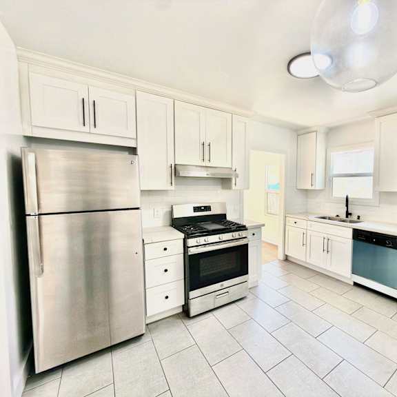 a kitchen with white cabinets and a stainless steel refrigerator.