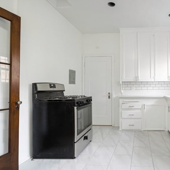 a kitchen with white cabinets and a black stove top oven.
