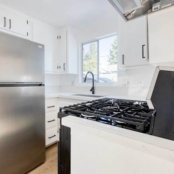 a modern kitchen with a stainless steel refrigerator and a black stove top.