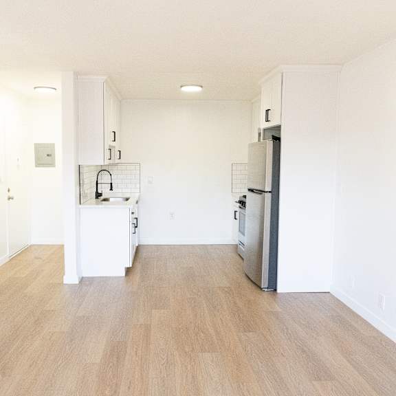 a kitchen with a refrigerator, sink, and cabinets.