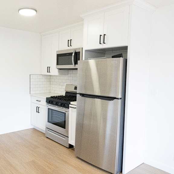 a modern kitchen with a stainless steel refrigerator, microwave, oven, and sink.