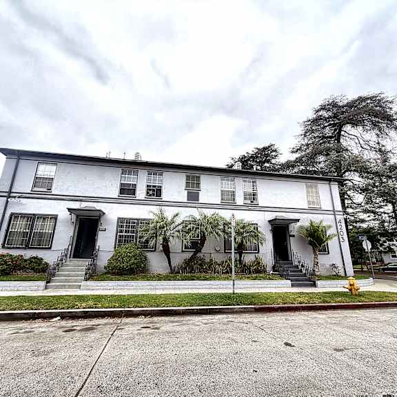 a white two-story house with a grey car parked in front.