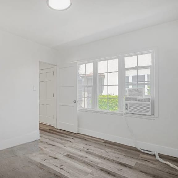 a room with a white door, a window with a white frame, and a light on the ceiling.
