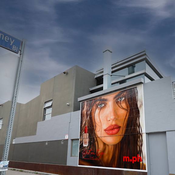 a large billboard with a woman's face on it is on the side of a building.