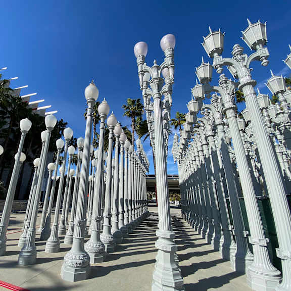 a row of white street lamps are lined up on a sidewalk.