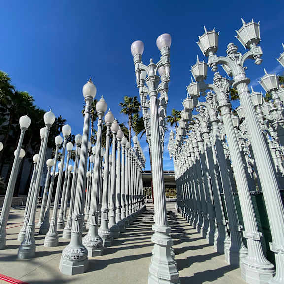 a row of white street lamps are lined up on a sidewalk.