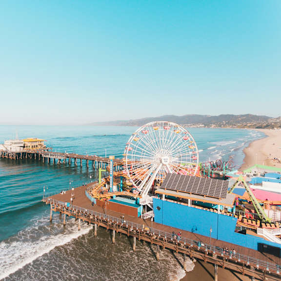 a pier with a ferris wheel and a building with solar panels on the roof.