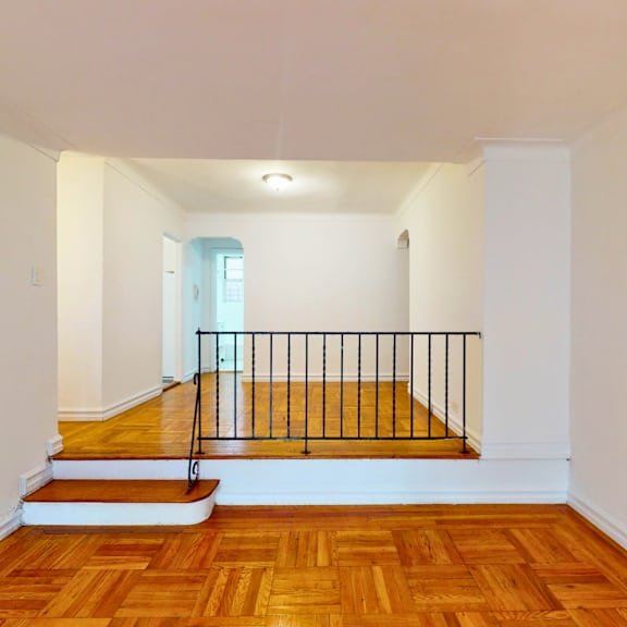 a room with wooden floors and a staircase leading to a balcony.