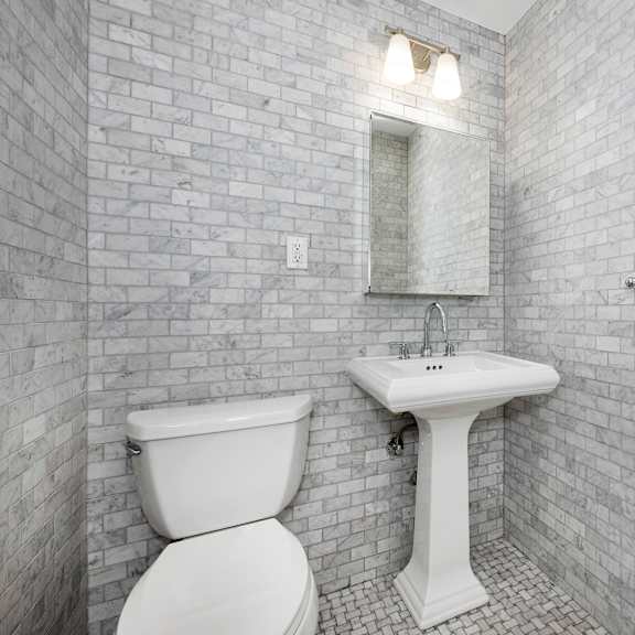 a white toilet and sink in a bathroom with a brick wall.
