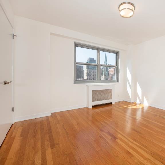 a room with wooden floors and a window overlooking a cityscape.