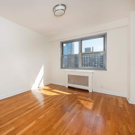 a room with wooden floors and a window overlooking a cityscape.