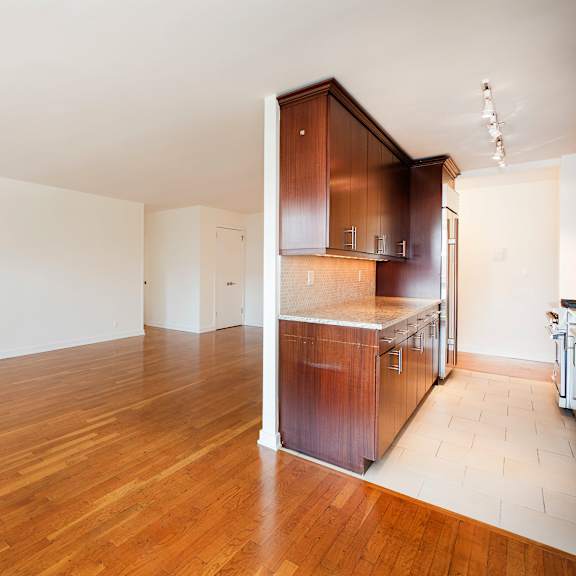a kitchen area with wooden floors and a white wall.