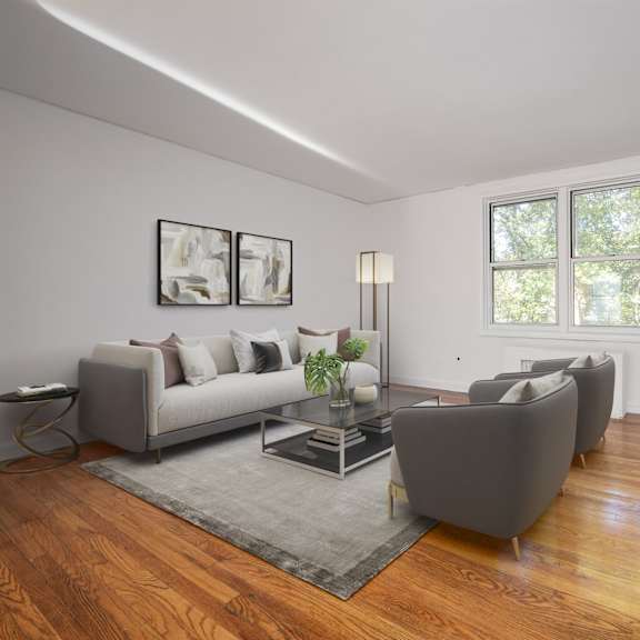 a living room with a grey couch, a grey chair, a white desk, and a bookshelf.