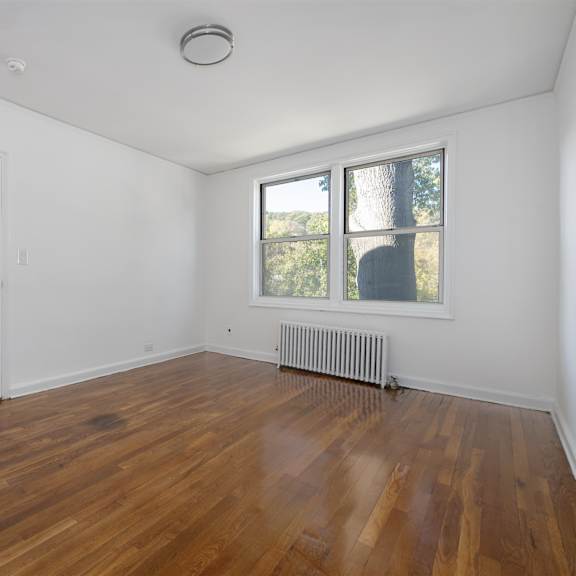 a room with wooden floors and a window showing trees outside.