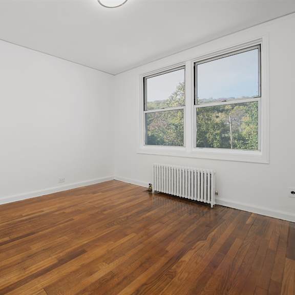 a room with wooden floors and a window showing trees outside.