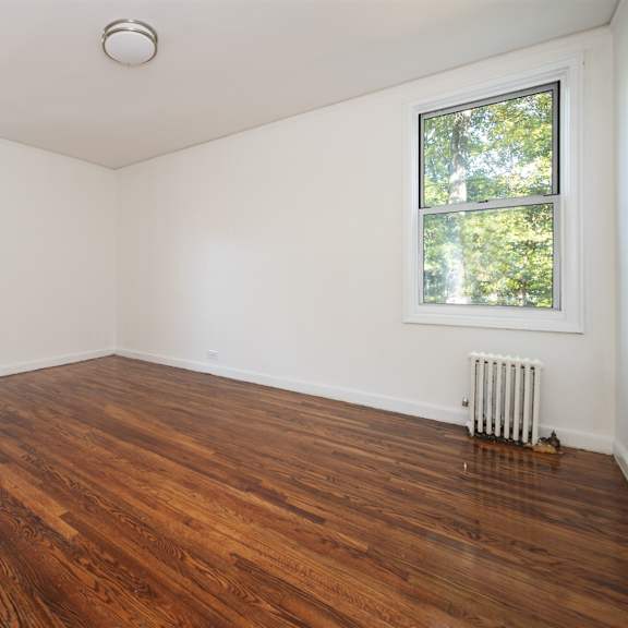a room with wooden floors and two windows.