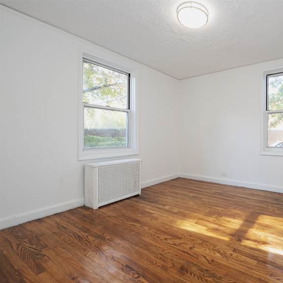 a room with wooden floors and two windows.
