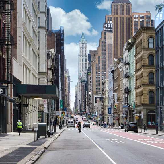 a city street with buildings on both sides and a few pedestrians walking.