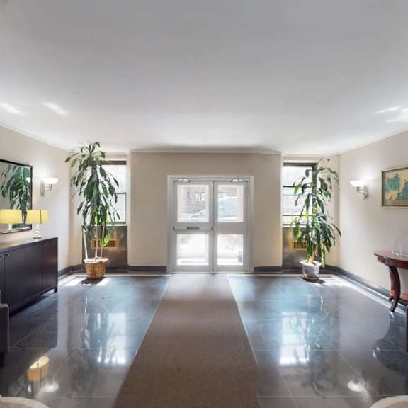 a spacious room with a large rug in the middle and a door at the end.