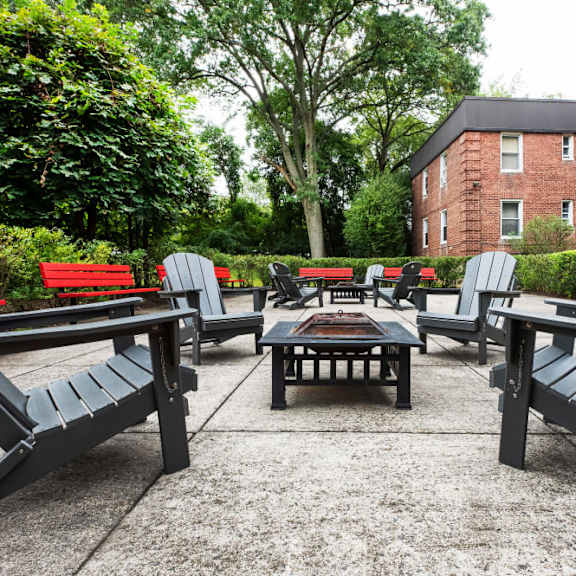 a patio with black benches and a table surrounded by greenery.