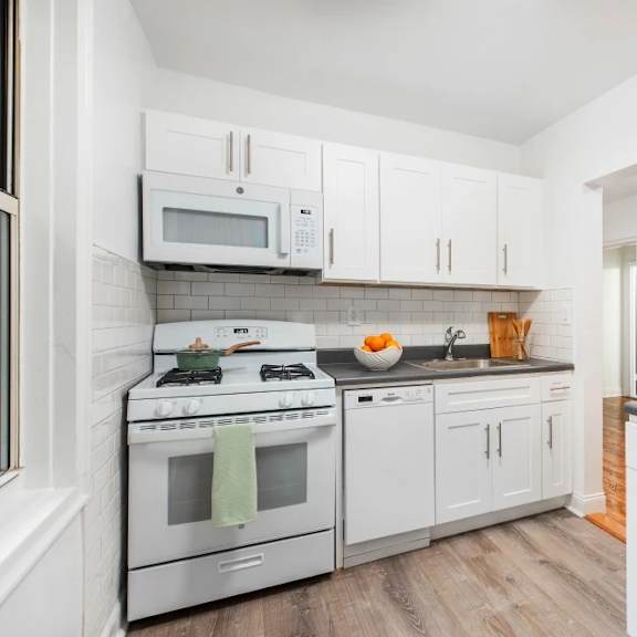 a white kitchen with a stove, microwave, and refrigerator.
