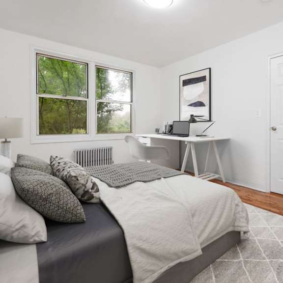 a bedroom with a bed, desk, and window.
