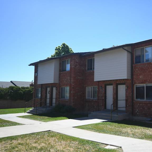 a red brick house with white siding and a sidewalk